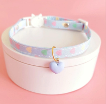 Pastel blue heart print choker with light blue webbing white cat buckle and matte purple heart pendant on white jewelry box display