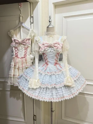 Pastel blue sweet lolita JSK jumper skirt with tiered ruffled lace hem and pink ribbon bow accents displayed on dress form