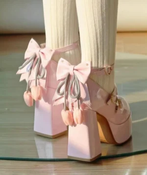 Pastel pink classic Lolita platform heel shoes with detachable tulip bow and heart-shaped buckle ankle straps, rear three-quarter view with beige ribbed crew socks