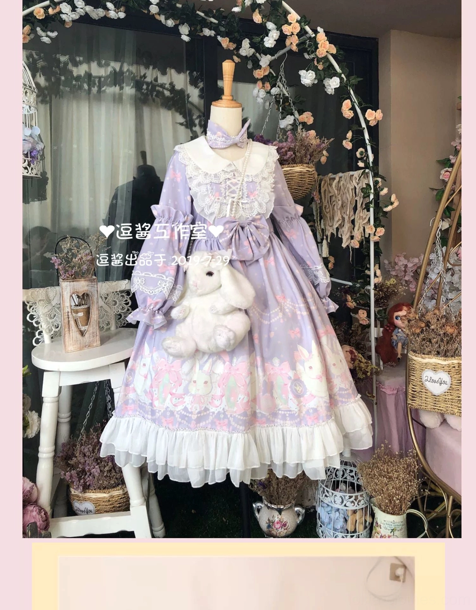 Pastel purple rabbit print Lolita OP dress front full shot on dress form mannequin with white doll collar, dramatic front bow centerpiece, paired with rabbit plush shoulder bag