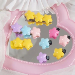 Collection of assorted pastel star-shaped hair clips in sweet lolita colors displayed on pink heart-shaped vanity mirror with lace trim
