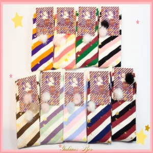 Overhead flat lay display of multiple pastel stripe lolita crew socks in various colorways with star-themed background and decorative gift box packaging with fluffy pom-pom details