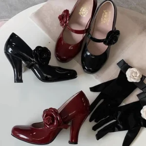 Patent leather Lolita Mary Jane block heel shoes overhead flat lay on light pink fabric black and burgundy colorway with large rose ornament ankle strap and paired black flower-decorated gloves