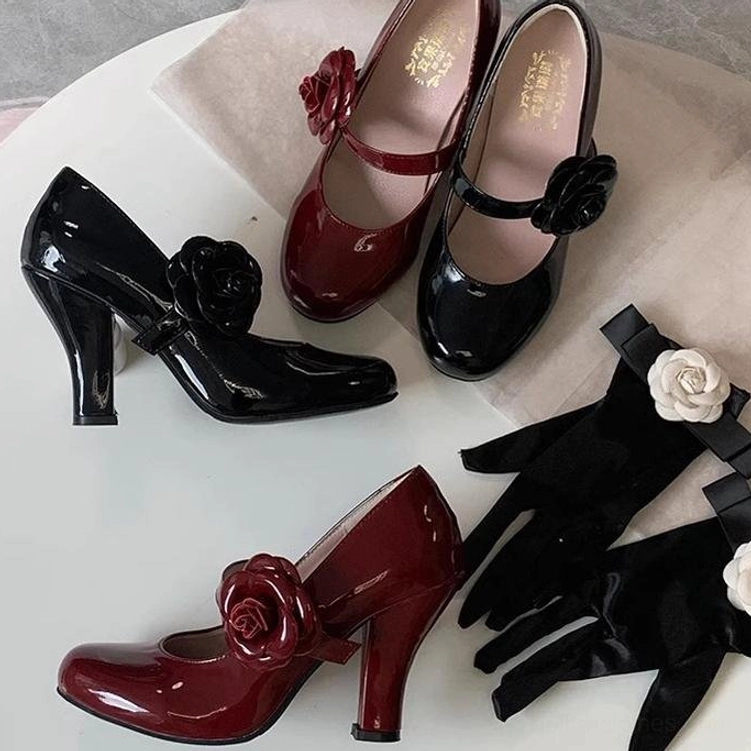 Patent leather Lolita Mary Jane block heel shoes overhead flat lay on light pink fabric black and burgundy colorway with large rose ornament ankle strap and paired black flower-decorated gloves