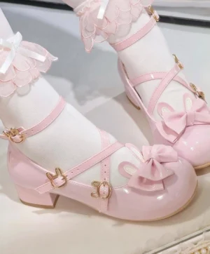 Patent pink Sweet Lolita bunny accent heels featuring gold bunny head buckles on cross straps, glossy leather finish, chunky block heel and decorative bow detail, paired with pink ruffled lace ankle socks