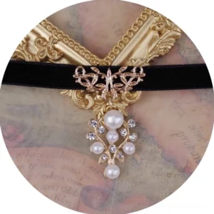 Pearl ball pendant lolita choker overhead circular view showing black velvet band with gold filigree clasp and faux pearl rhinestone pendant on vintage aged paper background