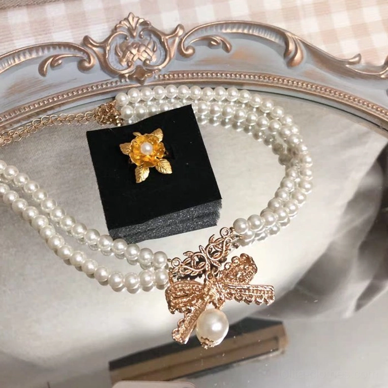 Pearl chain bow lolita choker necklace jewelry detail macro photography showcasing white pearl beads texture and golden bow pendant craftsmanship, close-up jewelry lighting, product specification reference