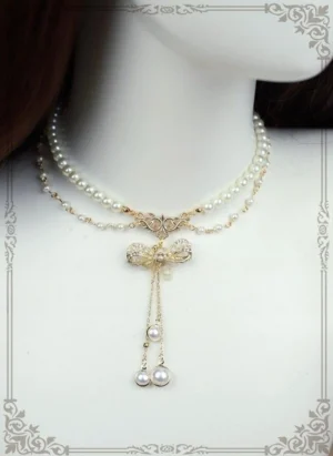 Close-up front view of pearl choker necklace with filigree gold bow and gemstone inlays, layered pearl chains with bottom pearl pendants on mannequin neck - lolita accessory detail