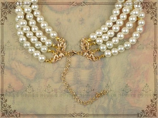 Rear view side flat lay of classic pearl choker necklace showing gold jewelry clasp, adjustable extension chain, and secure pearl strand connections on vintage patterned paper backdrop for Lolita accessories