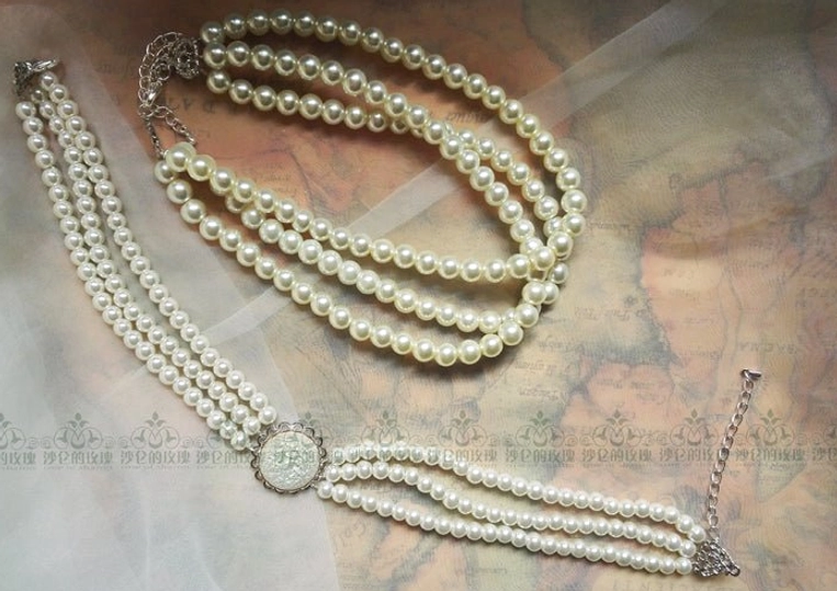 Mixed pearl layered necklace set flat lay on vintage map background, including multi-strand short choker and long lariat pearl necklace with round silver pendant and hardware