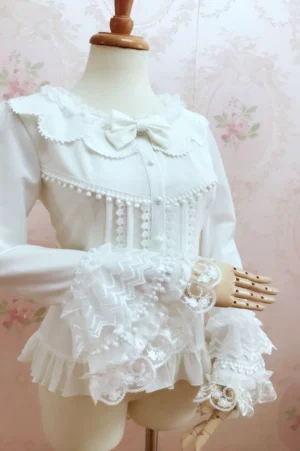 Sweet Lolita blouse three-quarter front view showing faux pearl buttons lace ruffled princess sleeves and pom-pom trim on mannequin