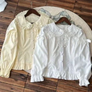 Long-sleeve lolita blouse with bishop sleeves and ruffled cuffs, peter pan collar design in beige and off-white, flat lay on wooden hangers showing front button placket and lace trim details