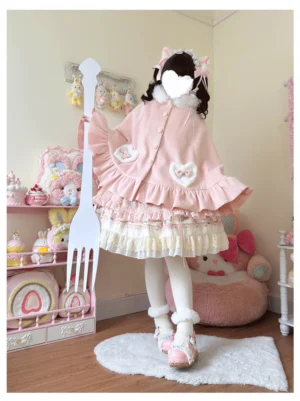 Pink bunny ear hooded kawaii lolita cape with fuzzy heart patches and ruffled hem worn on full-body mannequin in pastel bedroom setting