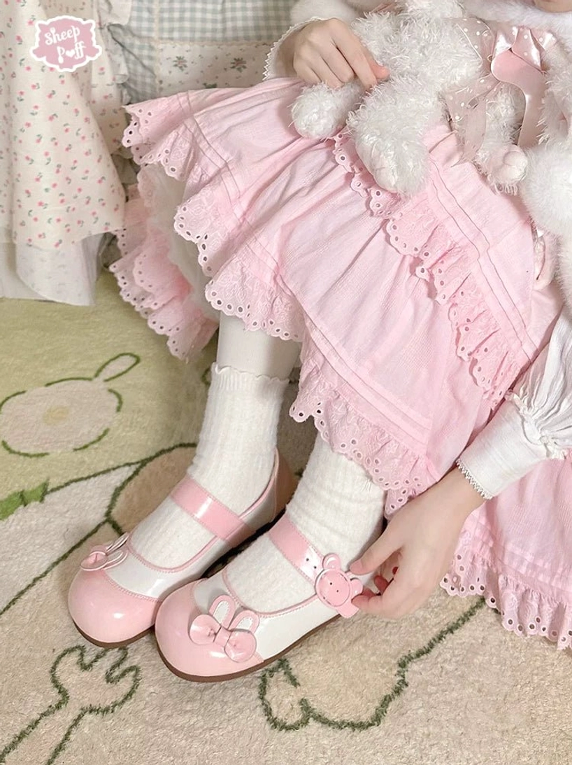 Pink bunny ear lolita flat shoes worn with pink frilly skirt and cartoon animal rug showing bunny-shaped strap buckle and kawaii styling in sweet lolita outfit