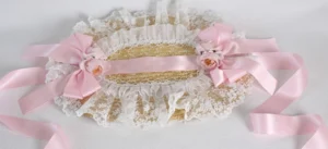 Pink country lolita straw hat flat lay top view showing white ruffled lace border, dual pink satin bows with flower decorations, and trailing pink ribbons