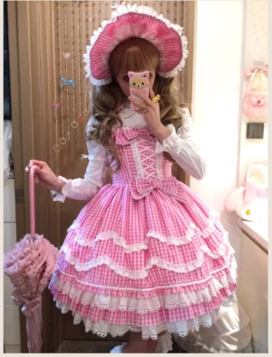 Old school Lolita jumper skirt dress in pink gingham with heart-shaped lace details, mirror selfie full-body front view showing complete coordinate with matching bonnet and pink lace parasol handle accessory
