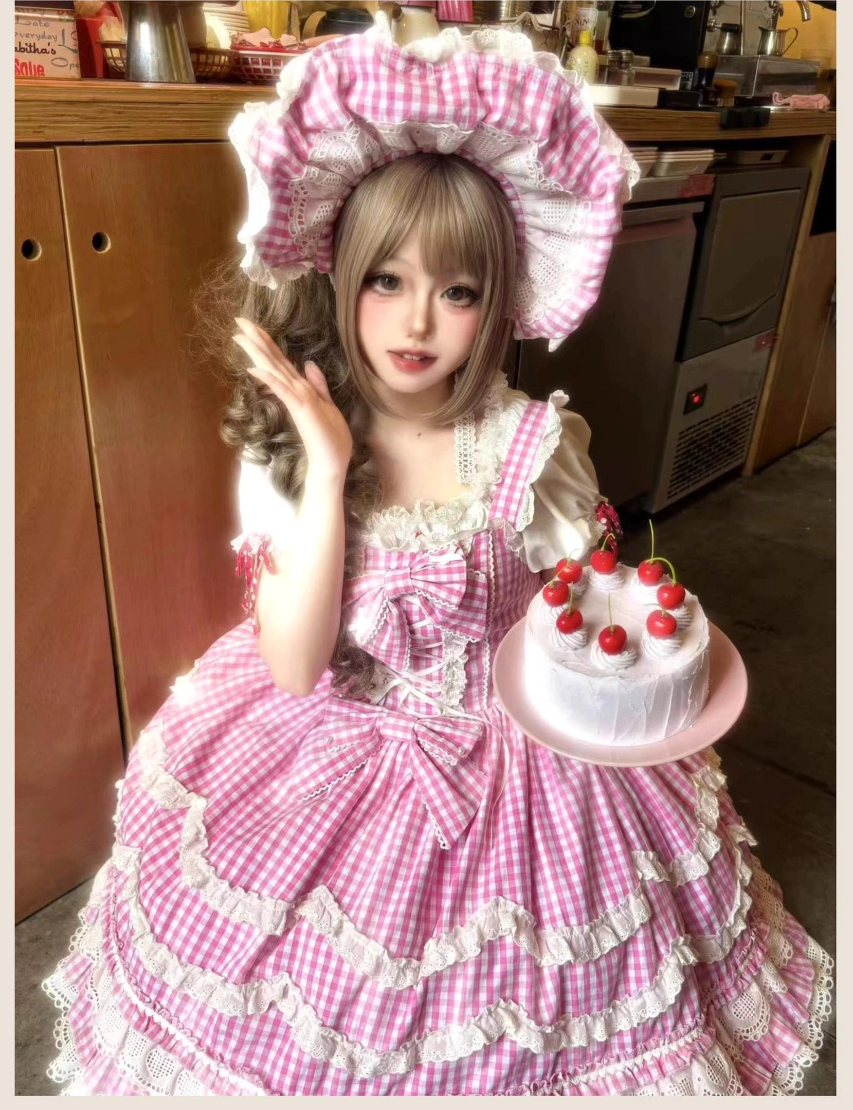 Old school Lolita jumper skirt in pink gingham with petal ruffles and decorative white lace trim, front three-quarter view kitchen interior background showing dress details with food styling accessory