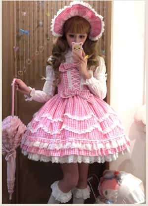 Pink gingham old school Lolita JSK dress with adjustable lace-up corset bodice and layered ruffle skirt featuring white lace trim, modeled in full-body three-quarter view with matching pink bonnet