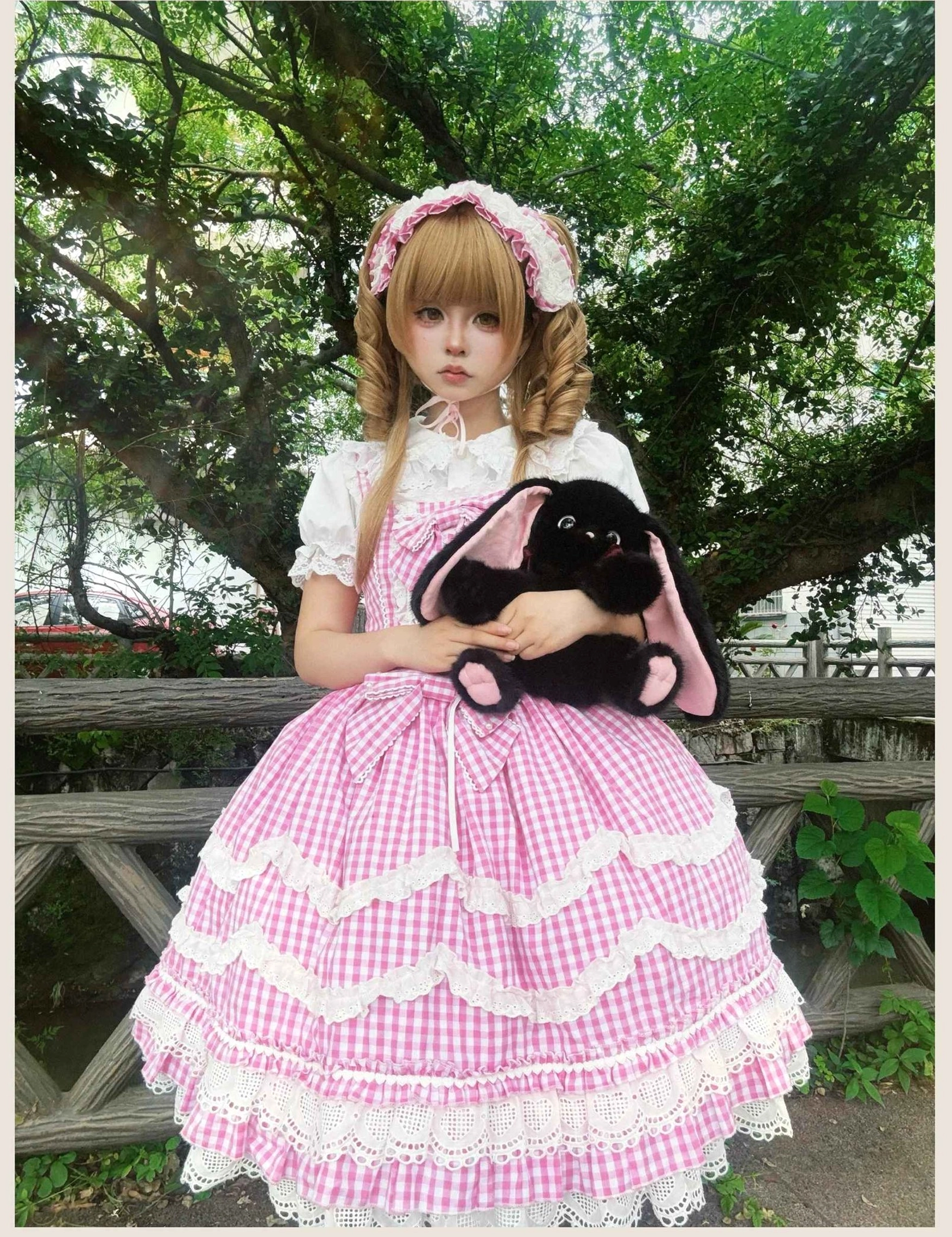 Vintage old school Lolita jumper skirt dress in pink gingham pattern, full-body front view outdoor setting showing complete coordinate with ruffled petal hem and white lace accents