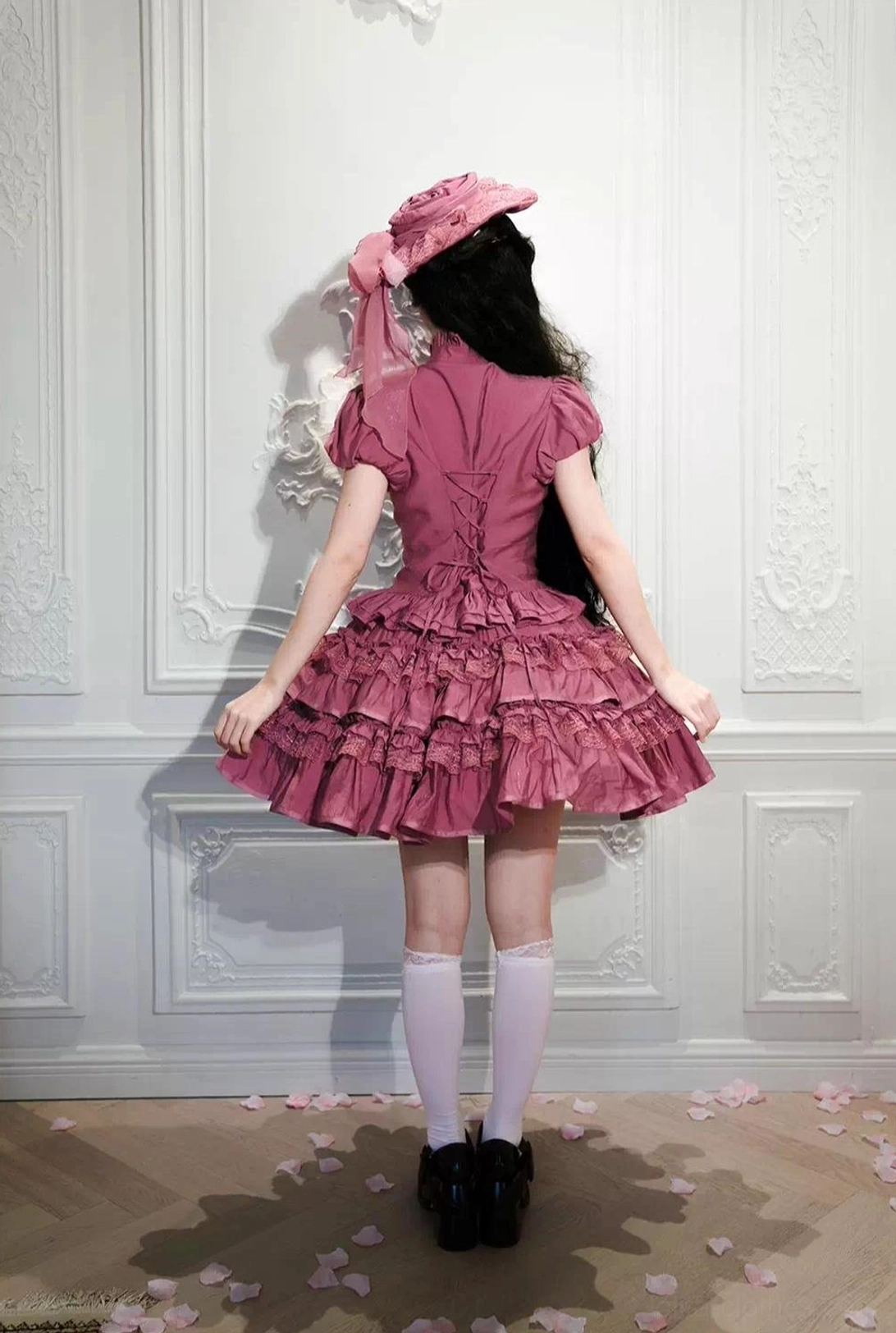 Pink short Gothic Lolita blouse worn on real model back full view minimalist room rose petals floor hair bonnet form-fitting ruffled bodice