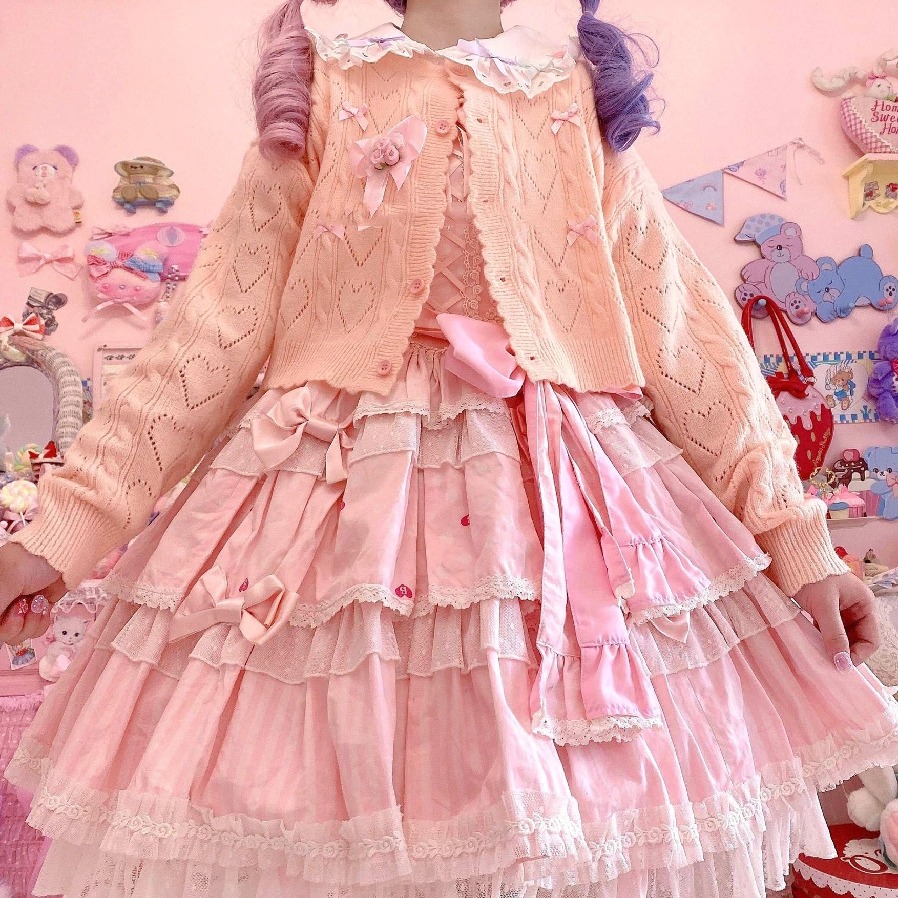 Pink hollow out long sleeve Lolita cardigan with lace collar and heart-shaped hollow knit texture featuring flower embellishments, paired with pink multi-tiered ruffled dress