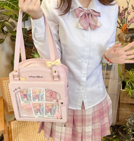 Pink kawaii lolita checkered itabag held in hand front view with yellow bow anime card display window jk uniform