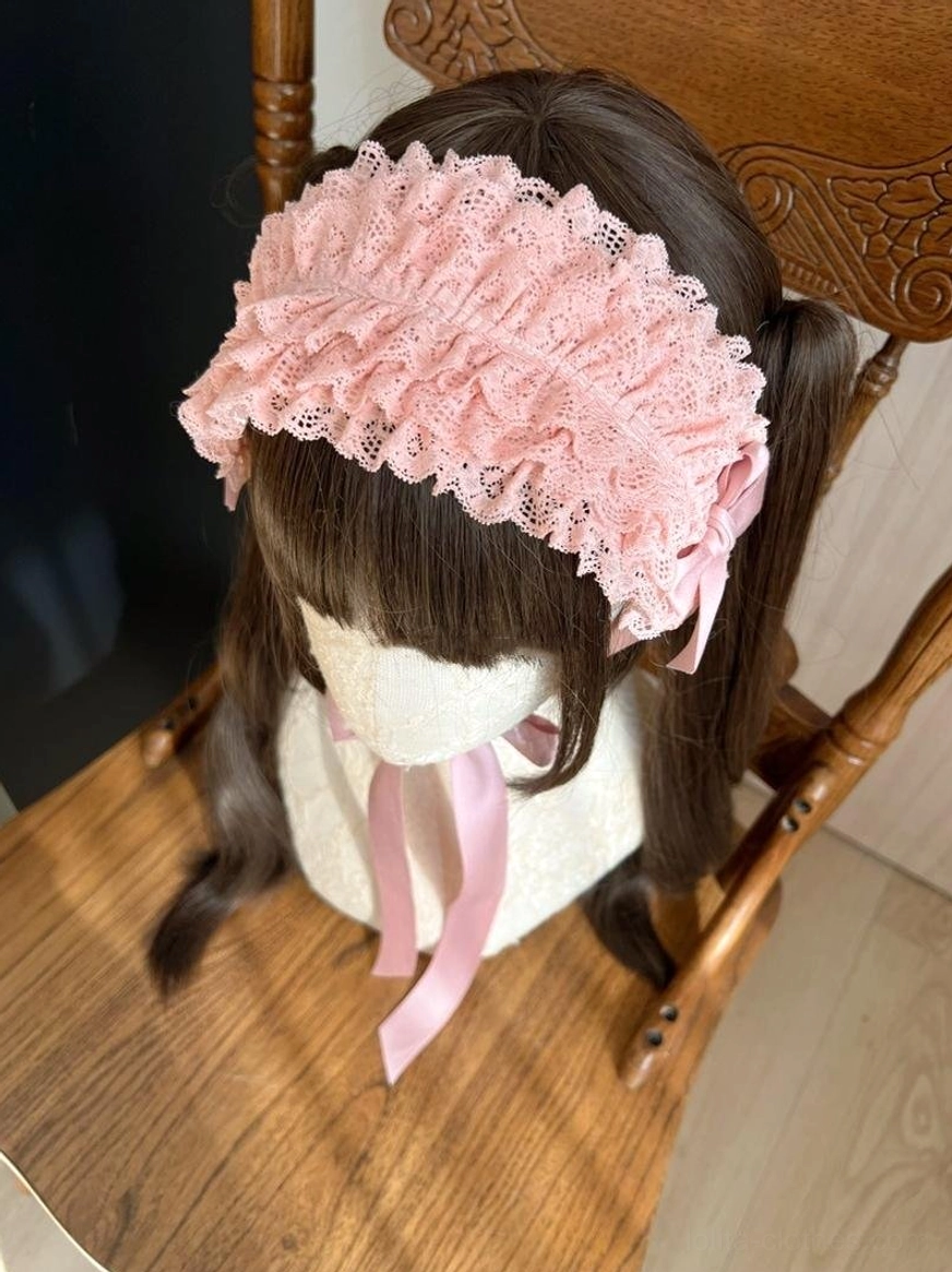 Overhead front view of pink ruffled lace KC headband featuring central satin bow decoration on mannequin with coordinated hairstyle