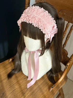 Pink lolita KC headband side profile view showing layered ruffled lace trim, matching pink satin bow, and decorative trailing ribbon on seated mannequin