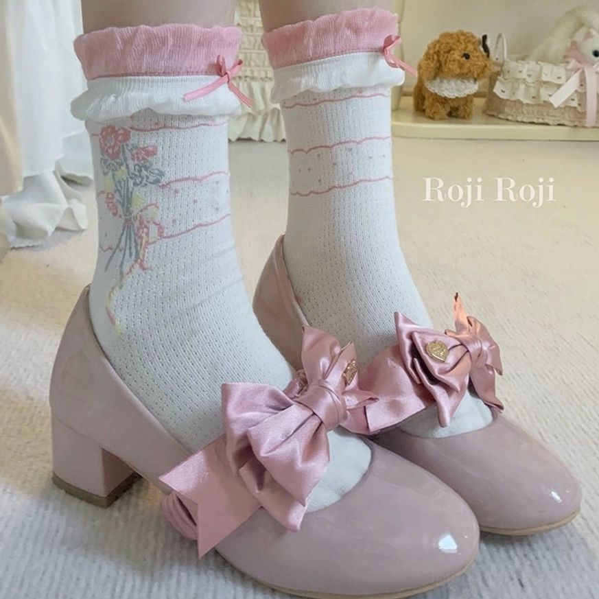 Pink bow Mary Jane heels coordinated with matching lolita ankle socks featuring pink ruffled cuffs tiny bow accent and white base with floral bouquet print front three-quarter angle