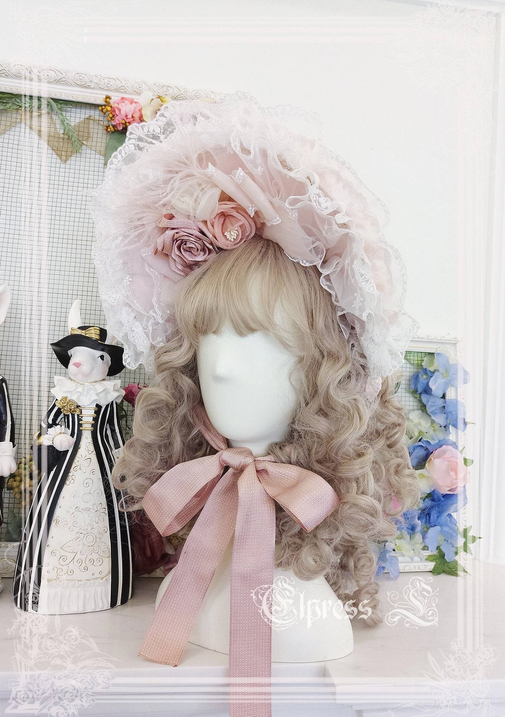 Pink lolita bonnet with artificial flowers lace flounce displayed on head mannequin with curled hair styling in Victorian Christmas aesthetic