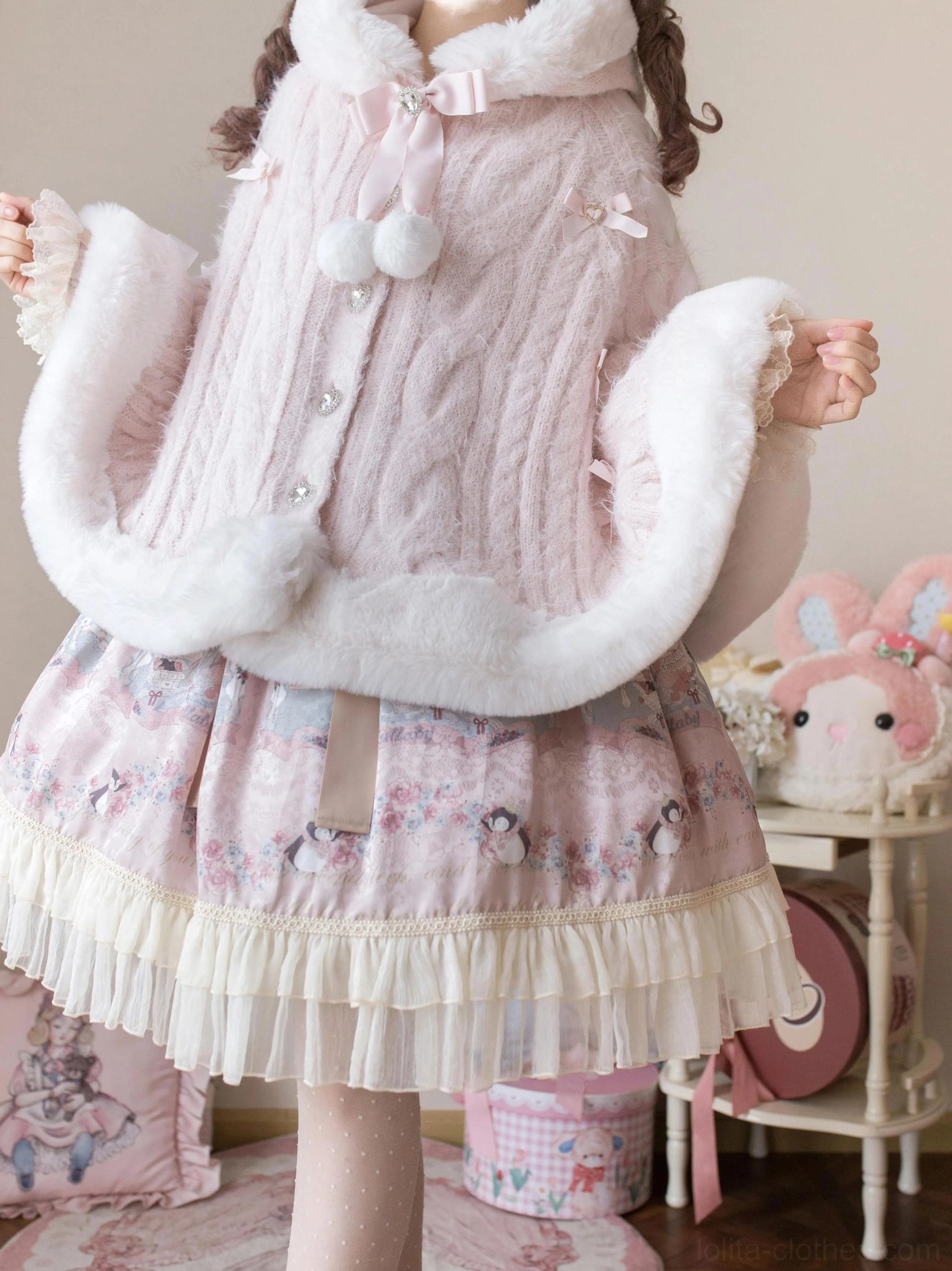 Pink faux fur lolita winter cape coat back three-quarter view showing bow at collar, front button fasteners, pom-pom decorations, plush sleeve trims