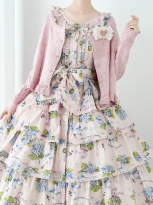 Pink lolita knit cardigan with ruffled lace crew neck and heart brooch worn over tiered hydrangea print dress front half body model display