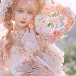 Half-body three-quarter view of model wearing complete pink Lolita outfit with bonnet, matching dress, mesh lace gloves and pink rose flower wand in outdoor garden setting