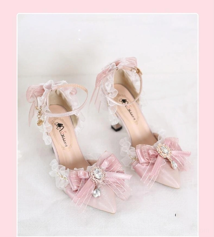 Pink lolita heels with ruffled mesh ankle trim and crystal embellishments on pink-bordered background, overhead angled view highlighting matching decorative bows and refined shoe construction details