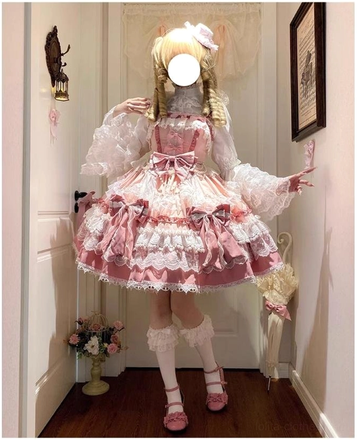 Back side view of pink-white lolita JSK dress on blonde twin-braid model spreading arms showing dress outline, puff lace sleeves, ruffled skirt with side bows