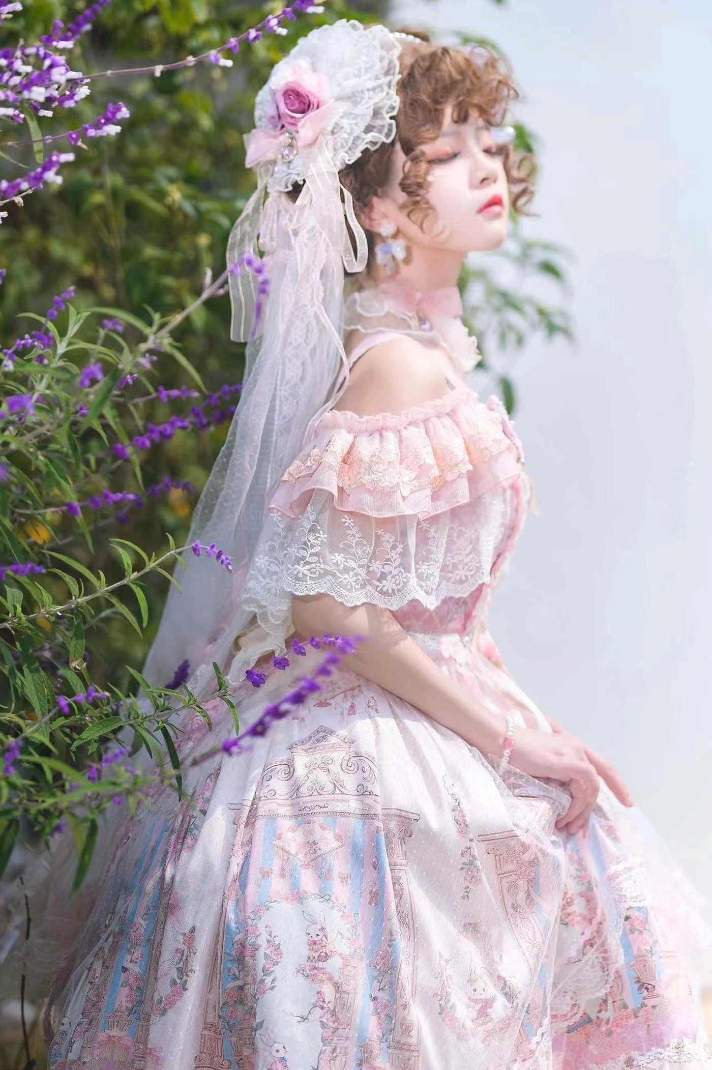 Pink off-shoulder wedding Lolita JSK dress with ruffled lace sleeves and vintage printed fabric, model wearing floral headdress and choker in lavender garden