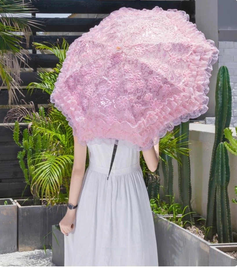 Back view of woman in white slip dress with pink lace Lolita parasol covering her, layered ruffled lace surface with metal umbrella shaft visible, outdoor tropical setting