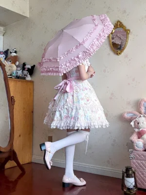 Model wearing sweet Lolita dress with pink waist bow holding pink frilled parasol back view vintage bedroom setting