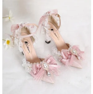 Pink lolita wedding pointed-toe heels with crystalline butterfly appliqués and pearl charms on soft daisy background, overhead flat lay view showing delicate ribbon bows and sheer ruffled trim details