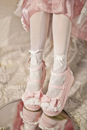 Model's feet wearing pink Milky Puff sweet Lolita platform heels with bow and lace trim, paired with white lace socks and pink Lolita skirt, displayed on vintage lace table backdrop