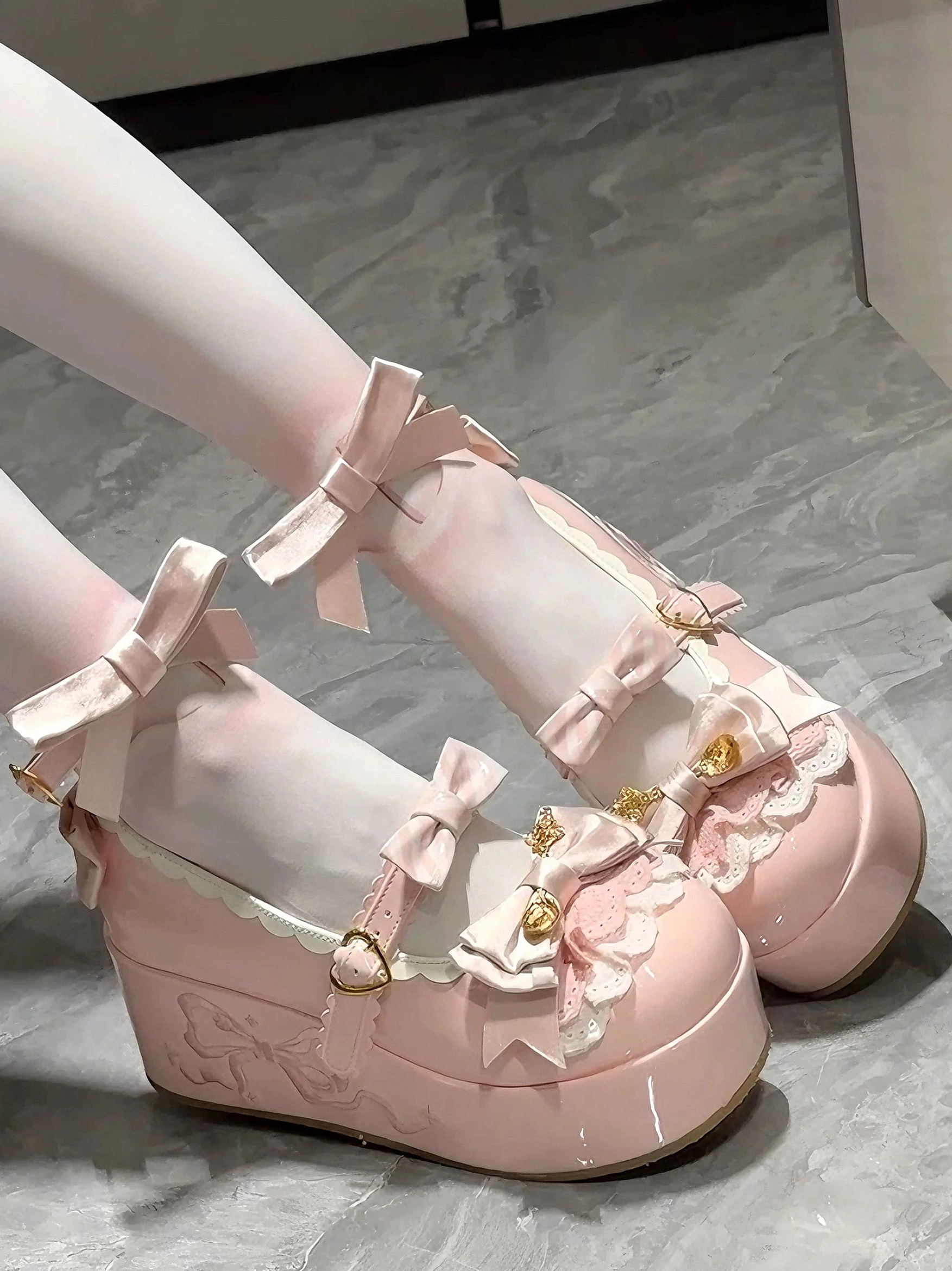 Pink mousse roll sweet lolita platform shoes worn on legs showing thick wedge platform ankle bow strap and lace ruffles on marble floor