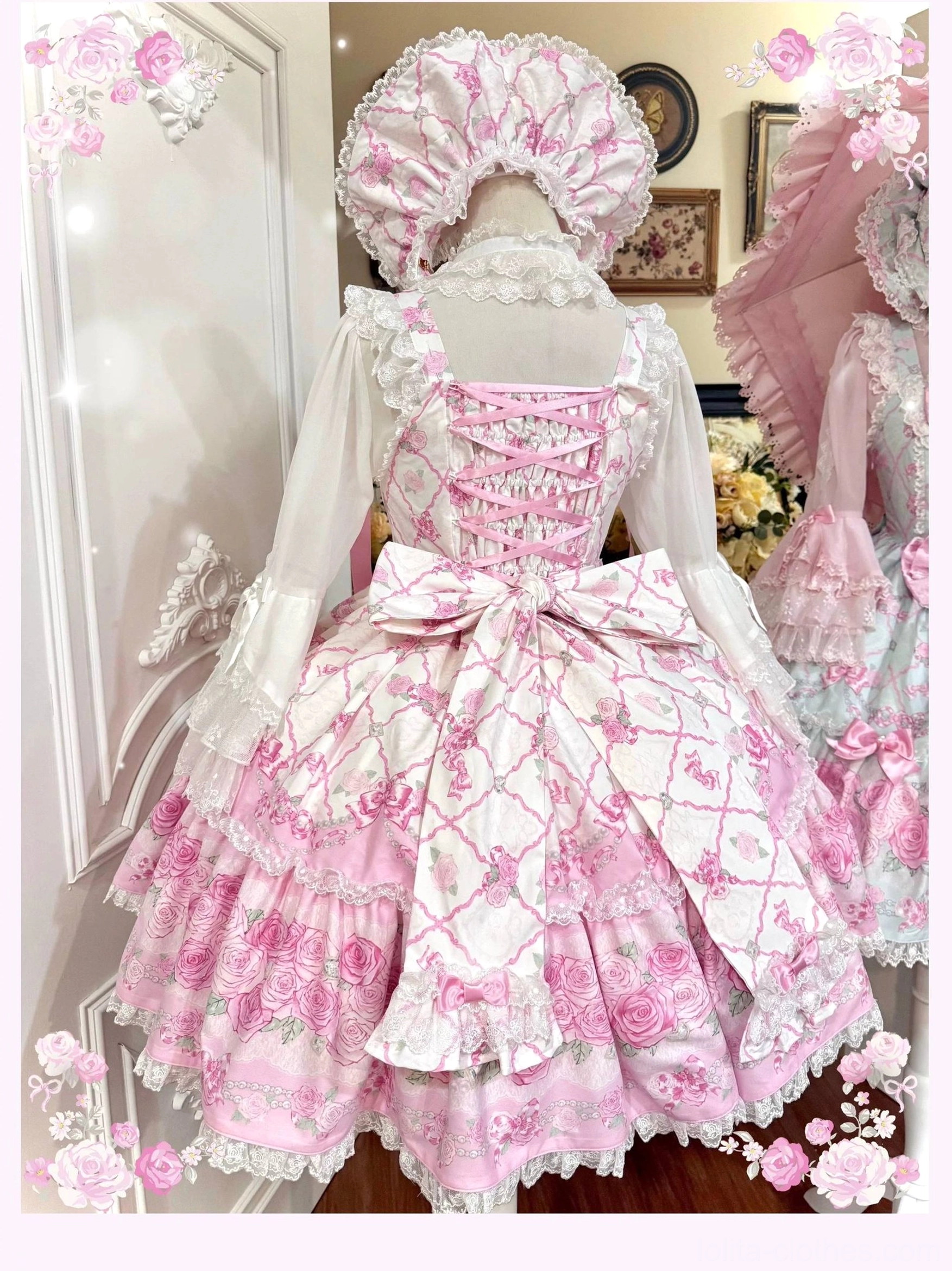 Back perspective of pink-based old school lolita jsk dress with lace-up corset construction, large back satin bow, ruffled bishop sleeves, and rose floral print, displaying traditional sweet lolita silhouette