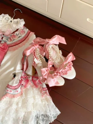Pink satin bow Lolita heels with pearl chain embellishments flat lay overhead view showing ruffled lace opening and ankle strap design