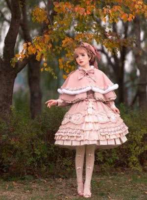 Pink plaid sweet lolita coordinated set full-length front view with tiered ruffle skirt and fur-trimmed capelet in autumn woodland setting