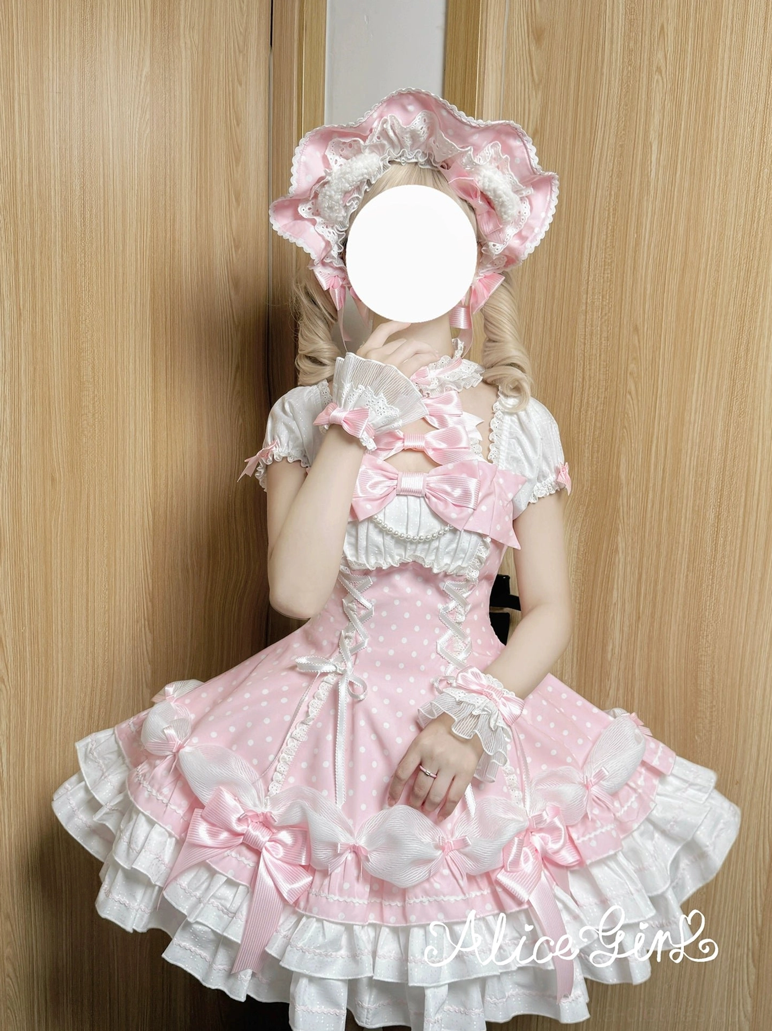 Pink polka dot Lolita dress close-up front view model wearing with matching bonnet halter neck chest bow decorations wooden background