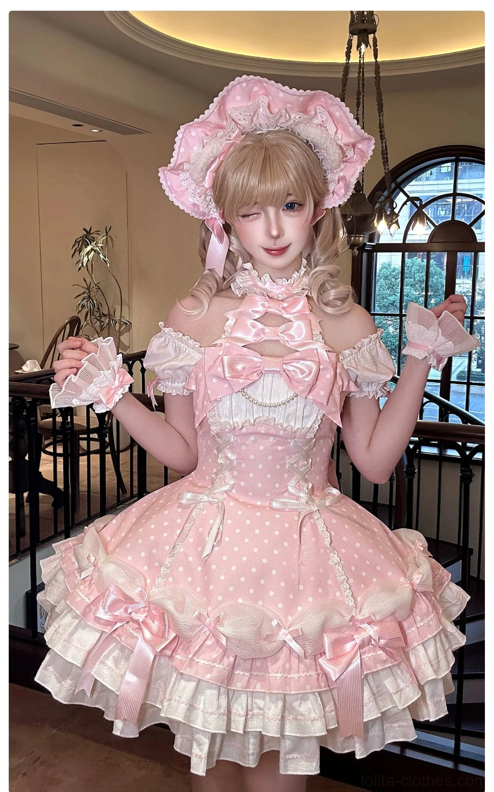 Pink polka dot off-shoulder Lolita OP dress model wearing with matching bonnet and cuffs vintage cafe interior arched windows