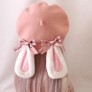 Back view of cute pink rabbit ear Lolita beret worn with long light pink wig, showing fluffy white outer rabbit ears with pink inner lining and printed pink satin bow on solid pink backdrop