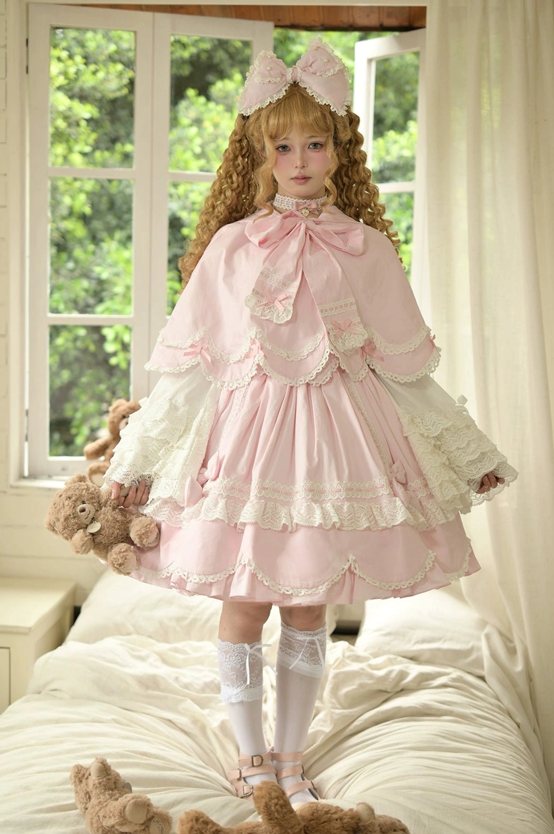 Pink lolita cape dress set front full shot curly blonde model standing on bed teddy bear sunny window bedroom layered ruffled lace skirt hair bow back detail