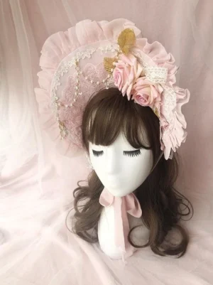 Front close-up view of pink rose-decorated sweet Lolita bonnet BNT with ruffled lace trim, artificial pink roses, delicate lace overlay, and pink neck ribbon displayed on mannequin with brown wig on pink fabric background
