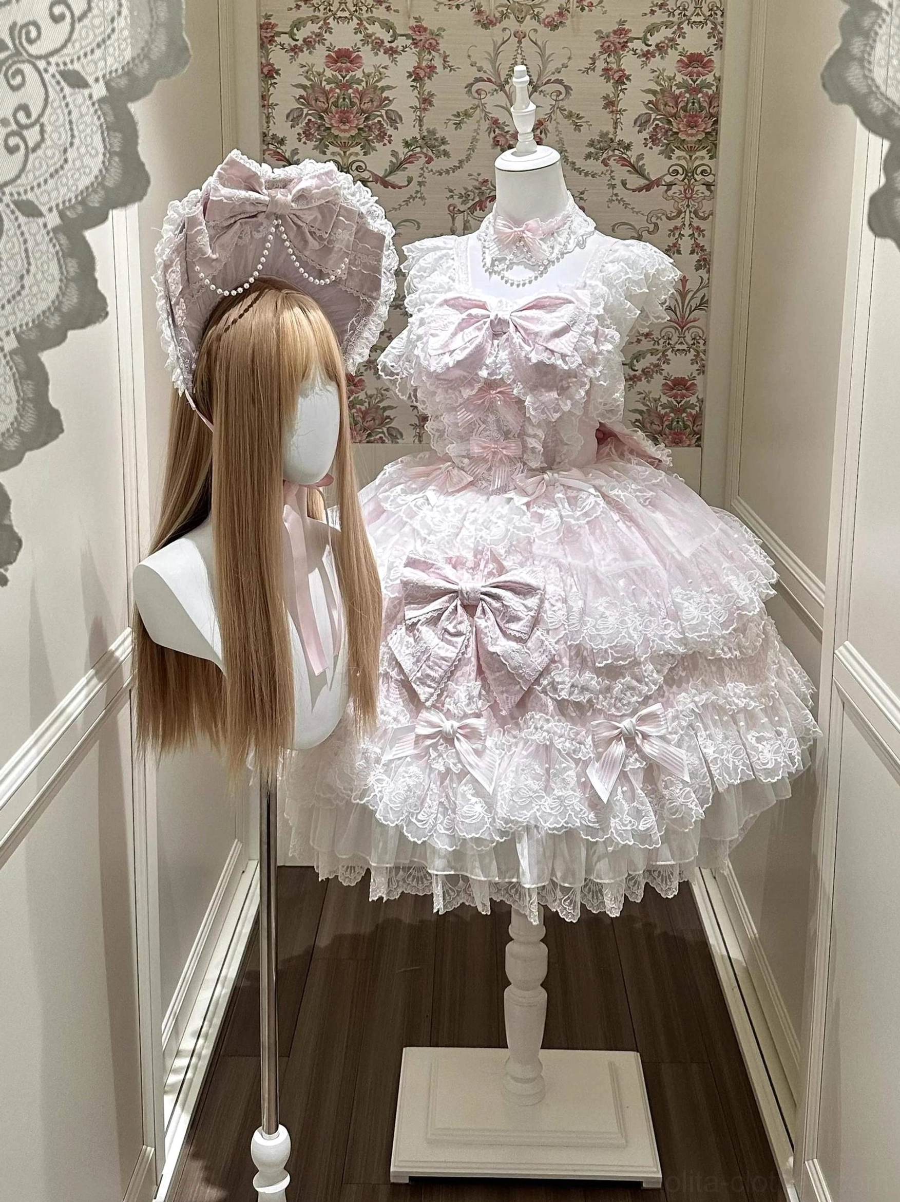 Pink Sakura Blossom Dream Sweet Lolita accessory set featuring pink BNT bonnet with pearl chain trim and delicate lace ruffled trailing, coordinating pink choker necklace with faux pearl embellishments, full front display on mannequin with vintage floral wallpaper backdrop showing complete Sweet Lolita coordinate styling